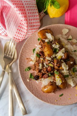 Beyaz şarap salmoriglio sosunda marine edilmiş Yunan öğütülmüş kuzu güveci ve yeni patatesli kalamata zeytin peyniri ve naneli garnitür.