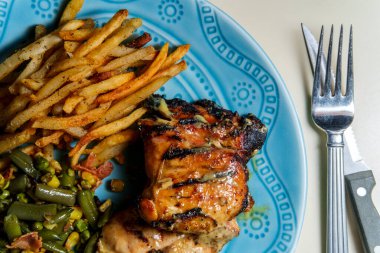 Ballı hardal ızgara tavuk budu, ev yapımı patates kızartması ve sebzelerle servis edilen yemek.