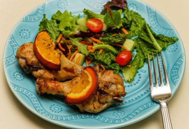 Kızarmış tavuk budu, portakal aromalı salata ve salata.