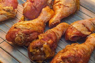 Çiğ tavuk bacakları metal pişirme tepsisinde marine ediliyor.