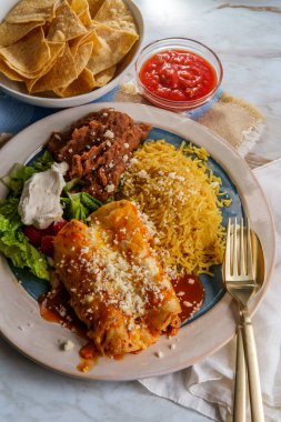 Geleneksel Meksika enchilada yemeği pilav ve yeniden kızartılmış fasulye ile servis edilir.