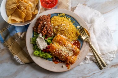 Geleneksel Meksika enchilada yemeği pilav ve yeniden kızartılmış fasulye ile servis edilir.