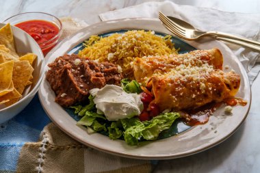 Geleneksel Meksika enchilada yemeği pilav ve yeniden kızartılmış fasulye ile servis edilir.