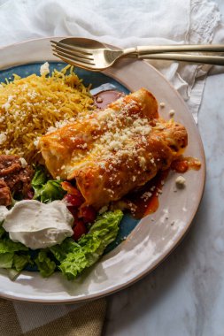 Geleneksel Meksika enchilada yemeği pilav ve yeniden kızartılmış fasulye ile servis edilir.