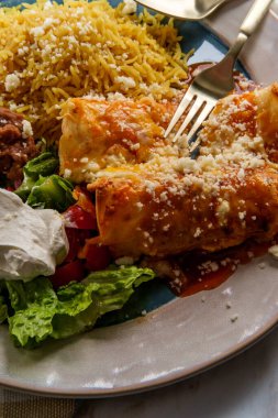 Geleneksel Meksika enchilada yemeği pilav ve yeniden kızartılmış fasulye ile servis edilir.
