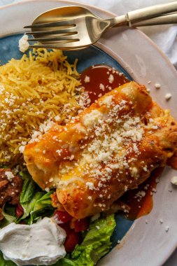 Geleneksel Meksika enchilada yemeği pilav ve yeniden kızartılmış fasulye ile servis edilir.