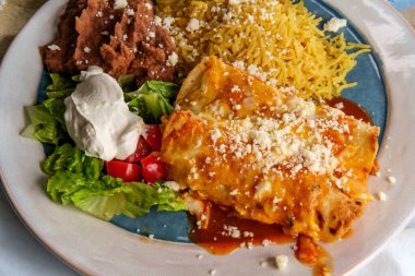 Geleneksel Meksika enchilada yemeği pilav ve yeniden kızartılmış fasulye ile servis edilir.