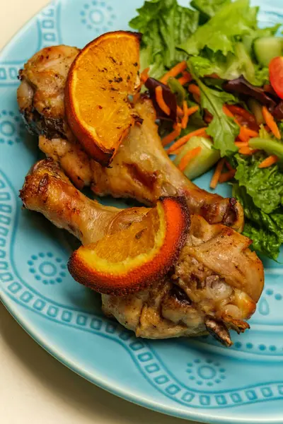 Kızarmış tavuk budu, portakal aromalı salata ve salata.