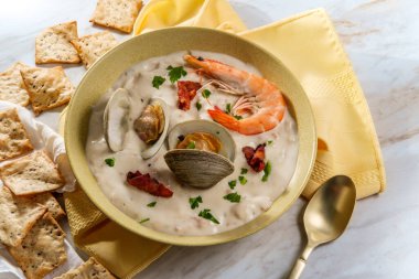 Taze sıcak New England midye çorbası, karides kraker ve maydanozlu garnitür.