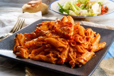 İtalyan yemeği kuyruklu karides penne alla vodka yanında pastırma ve salata.