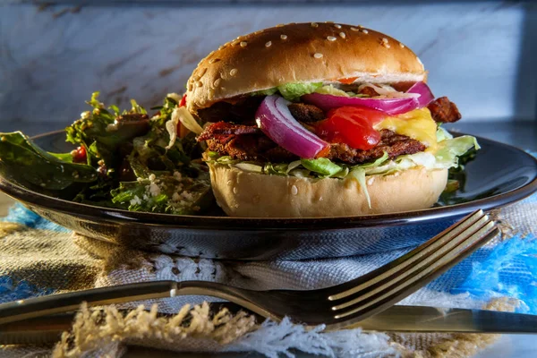 Angus beef cheeseburger topped with crispy bacon served with a side Greek salad