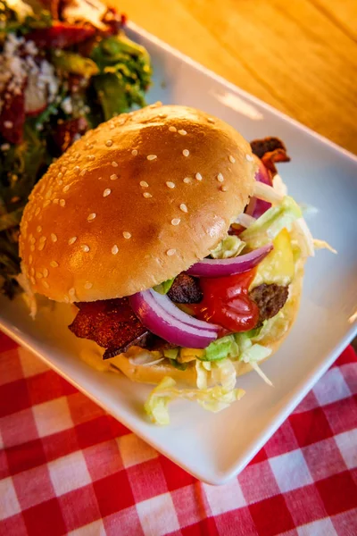 Angus beef cheeseburger topped with crispy bacon served with a side Greek salad