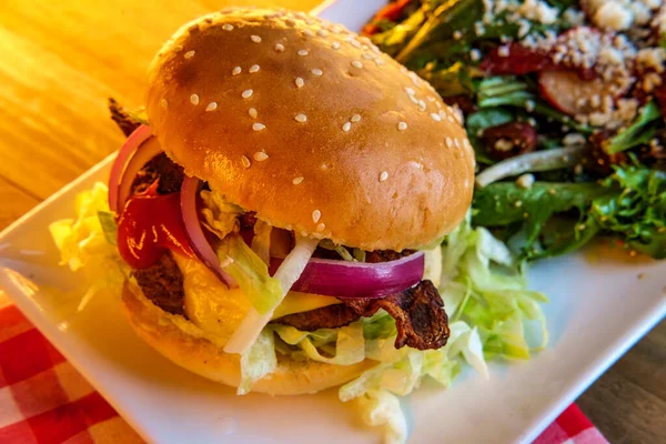 Angus beef cheeseburger topped with crispy bacon served with a side Greek salad