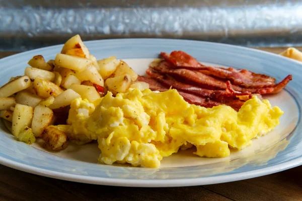 American breakfast food scrambled eggs with home fries and crispy bacon