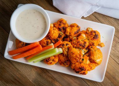 Vejetaryen karnabahar bufalo kanatları mavi peynir sosu ve dilimlenmiş havuç ve kereviz ile servis edilir.