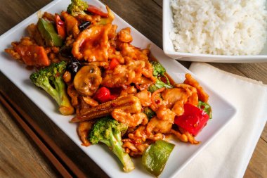 Chinese chicken with garlic sauce and sauteed mixed vegetables with a side of white rice clipart