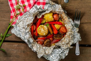 Izgara ızgara sosis folyo paketinde mısır var.