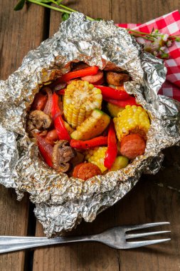 Izgara ızgara sosis folyo paketinde mısır var.
