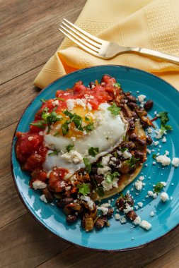 Meksika usulü huevos rancheros omlet sucuklu tostada ve üzerine salsa soslu siyah fasulye ve mısır tortilla üzerine queso fresco.