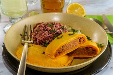 Birader ve limonata ile servis edilen kişniş garnitürlü baharatlı Jamaika bifteği ve mor pirinç.