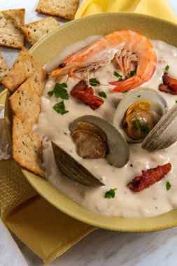 Taze sıcak New England midye çorbası, karides kraker ve maydanozlu garnitür.