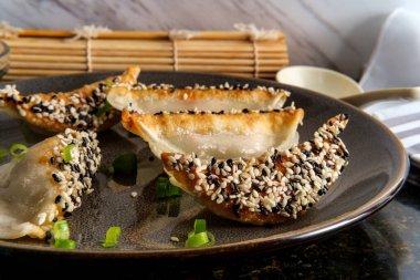 Çin usulü kızarmış sebzeli hamur tatlısı, siyah ve beyaz susam tohumları ve soslu fıstık ezmesi. 