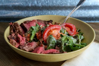 Pembe sulu biftek az pişmiş roka baharatlı yeşil salata ve mavi peynir soslu.