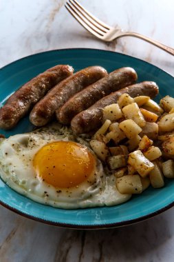 Kızarmış güneşli tarafı, sosisli ve patatesli Amerikan yumurtalı kahvaltısı.