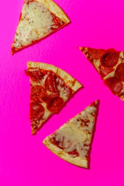 New York tarzı pizza dilimleri neon renkli arka planda sert ışıkla çekiliyor