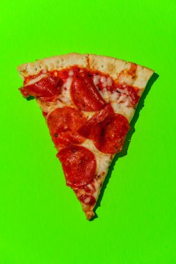 New York tarzı pizza dilimleri neon renkli arka planda sert ışıkla çekiliyor