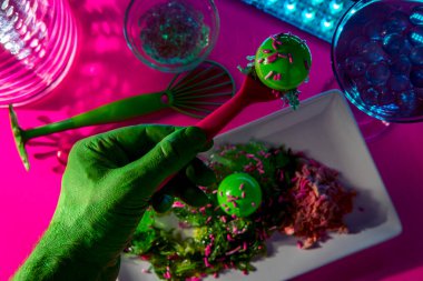 Uzaydan gelen bilim kurgu yeşil uzaylı süslü bir neon gece kulübünde yemek yiyor.