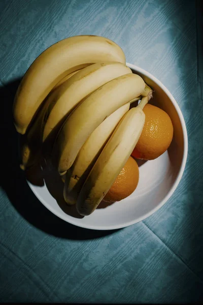 초록색 배경에 그릇에 오렌지와 바나나 — 스톡 사진