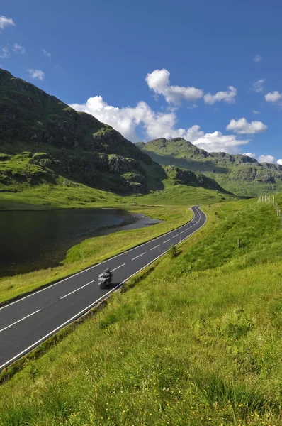 Fortkörning motorcykel på bergsväg i Skottland Royaltyfria Stockfoton