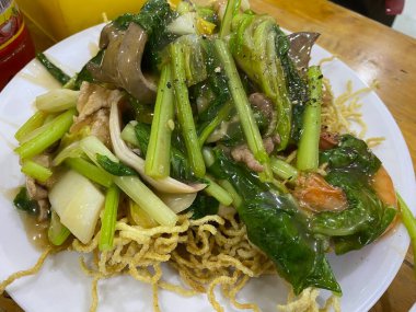 Assorted Asian stir-fried foods sizzling in a wok colorful vegetables meats and noodles savory aromatic sauce traditional flavorful cuisine vibrant street food or home-cooked meal presentation