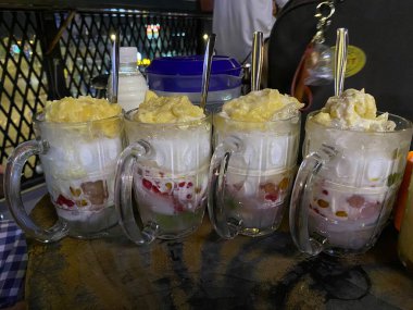 Durian Jackson meyveli jöle ve hindistan cevizi sütü ile renkli Vietnam Che Thai tatlısı tatlı tropikal ikramlı taze ve popüler sokak yemekleri canlı Asya lezzeti ve kültürü sergiliyor