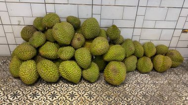 Pile of fresh durians and opened peels showing yellow creamy flesh tropical exotic fruit rich aroma popular in Southeast Asia natural market display authentic tropical produce scene
