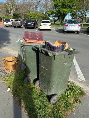 Çöp tenekesi kaldırım veya sokakta kapaklı standart atık konteynırını gösteriyor, temizliği ve kentsel çevre bağlamını vurguluyor