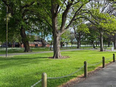 Christchurch 'deki Hagley Parkı manzarası Yeni Zelanda yeşil manzara ağaçları göl ve açık araziler huzurlu şehir parkı doğa eğlencesi ve dinlenme noktası.