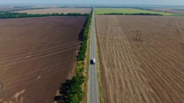 Bir kamyon güneşli yaz mevsiminde tarlaların içinden geçiyor. Taşımacılık kavramı kırsalda. İHA ateşi