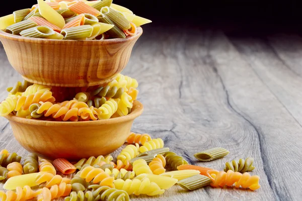 Eliche crudo y pasta tricolori penne en los cuencos de madera — Foto de Stock