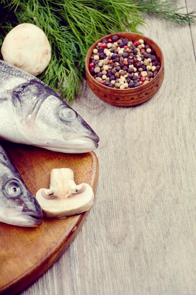 Peces de lubina crudos en el tablero de madera — Foto de Stock