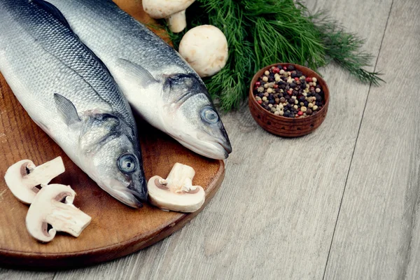 Peces de lubina crudos en el tablero de madera — Foto de Stock