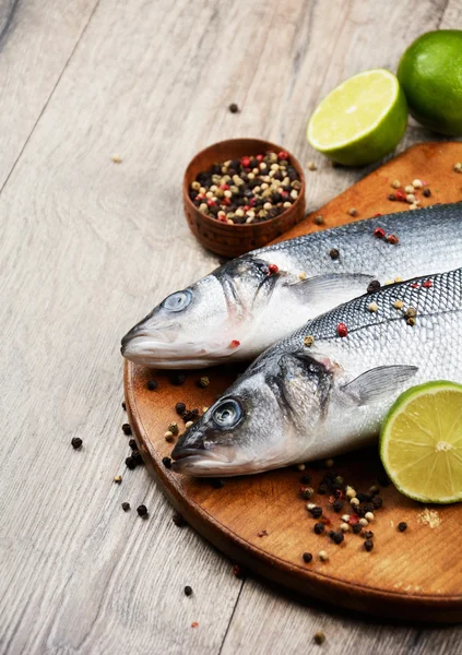 Peces de lubina crudos en el tablero de madera — Foto de Stock