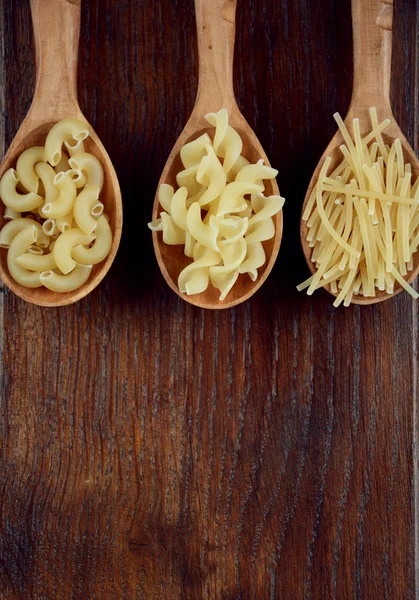 Cucharas de árbol con diferentes tipos de pasta — Foto de Stock