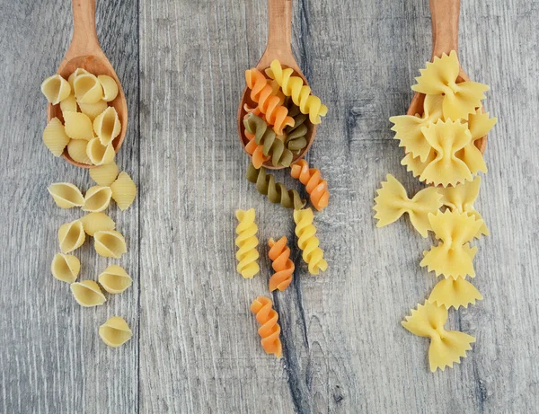 Tres tipos de pasta cruda en cucharas de madera — Foto de Stock