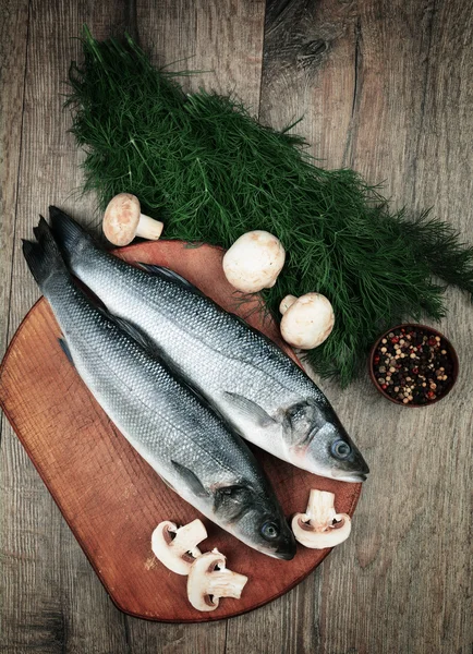 Peces de lubina crudos en el tablero de madera — Foto de Stock