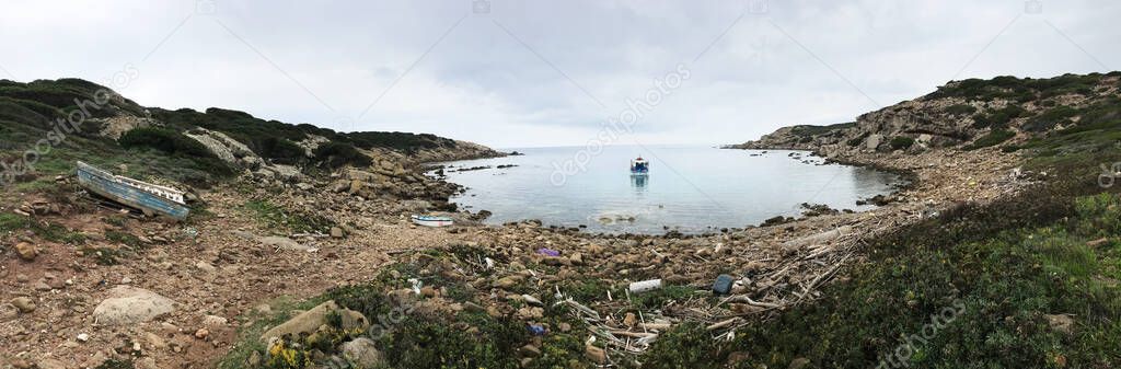 coastal view with fishing boat at cala del vino, alghero, sardinia, italy