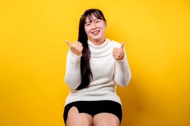 Gülümseyen yüzlü güzel bir Asyalı kadının portresi. Sıradan kıyafetler giyen Asyalı bir kadın. Tayland yaşam tarzı. Sarı arka planda parlak bir gülümseme.