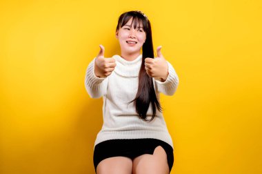 Gülümseyen yüzlü güzel bir Asyalı kadının portresi. Sıradan kıyafetler giyen Asyalı bir kadın. Tayland yaşam tarzı. Sarı arka planda parlak bir gülümseme.