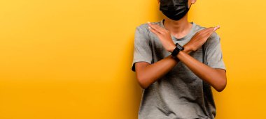Asian man preventing coronavirus covid-19. Man wearing black mask. prevent infection airway disease virus protection concept yellow backdrop